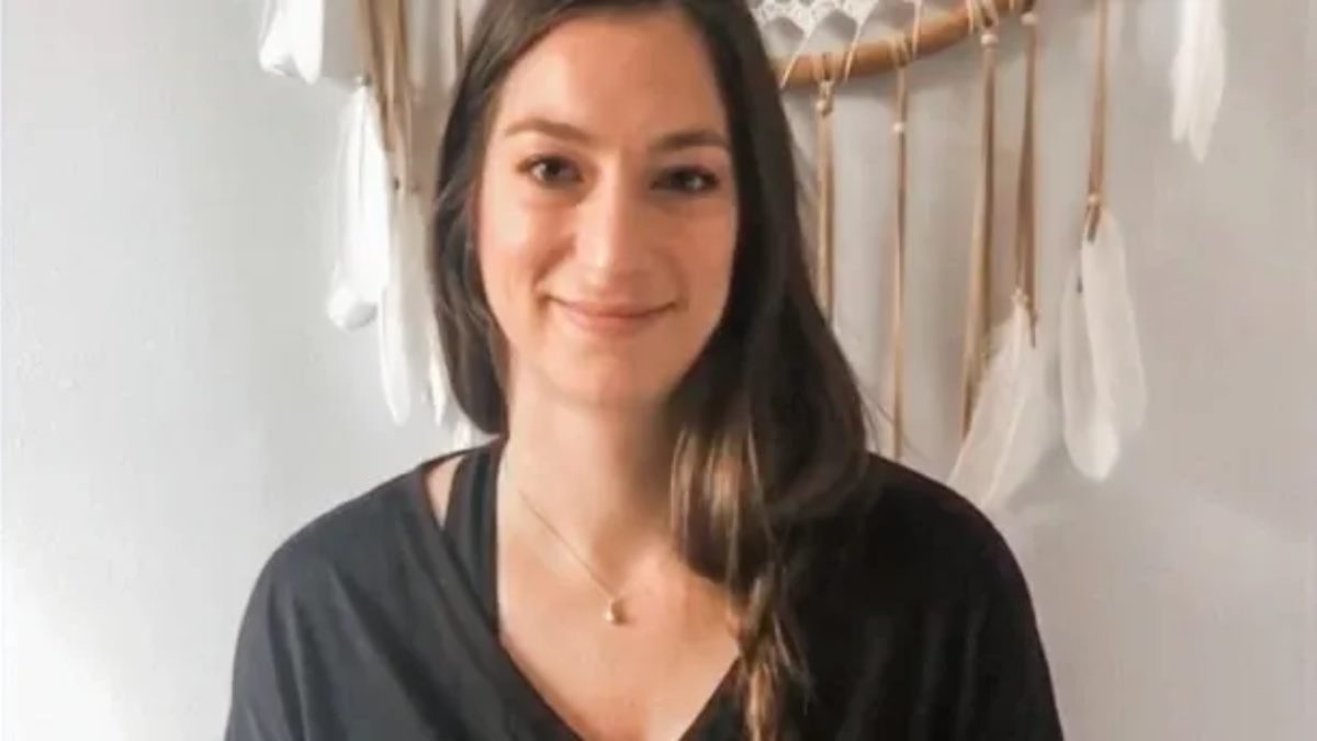 A woman smiling in front of a dreamcatcher