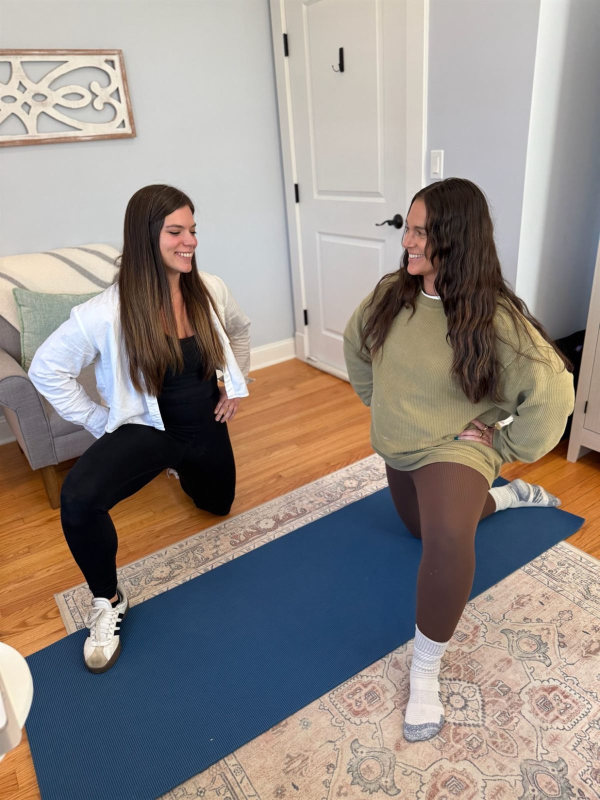 Physical therapist guiding a client through a kneeling lunge on an exercise mat